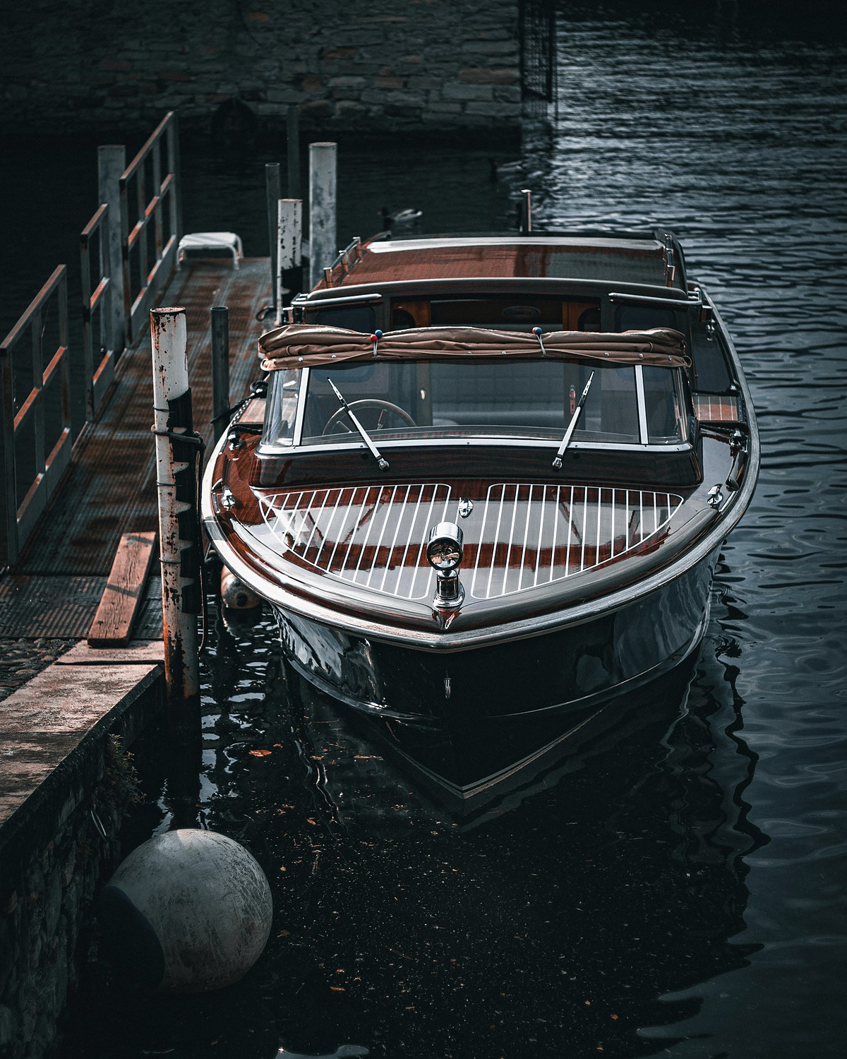 A varnished wooden launch moored at a quiet dock