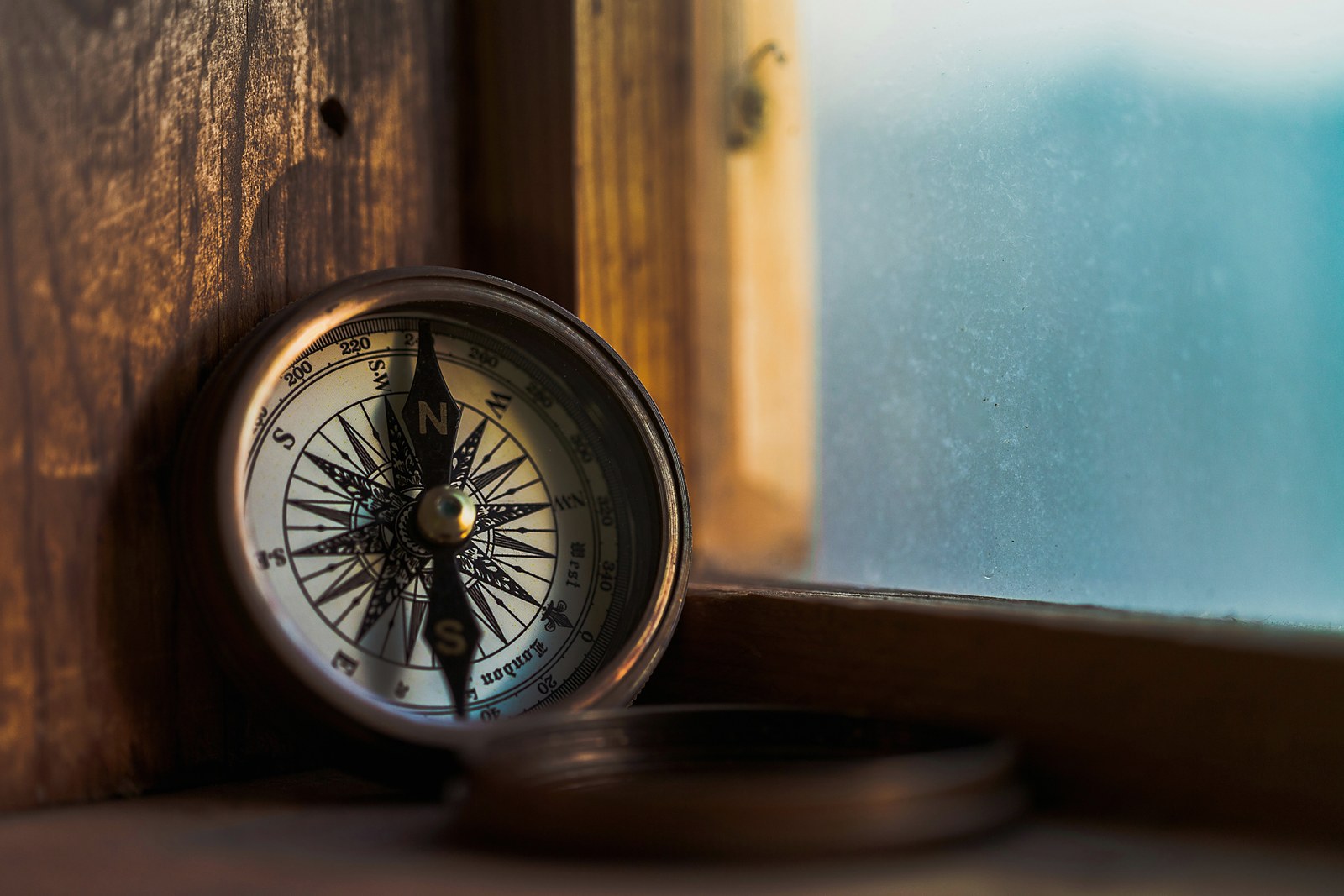 A pocket compass resting on a wooden ledge