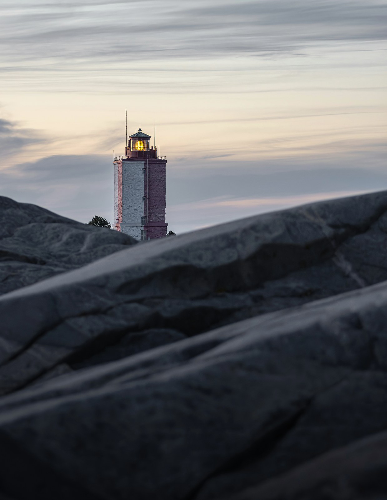 Lighthouse at dusk on a rocky shoreline